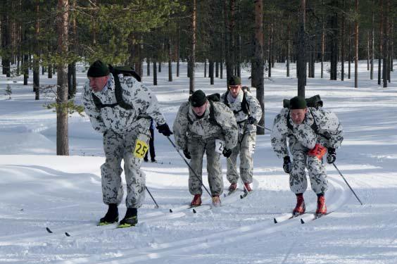 Alla olevassa kuvassa joukkueet odottavat lähtölaukausta Tanhuvaaran urheiluopiston kentällä. Prikaatin joukkue numero 8 aloittajina ylikersantti Arto Vesamo ja alikersantti Anton Koivisto. 3.