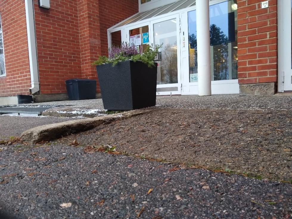 11 Sisäänkäynti B Sisäänkäynnin edessä on betoninen luiska, joka on riittävän loiva ja luistamaton märkänäkin. Luiskan ympärillä on asfalttia ja harmaata kivilaattaa, joten se ei erotu ympäristöstään.