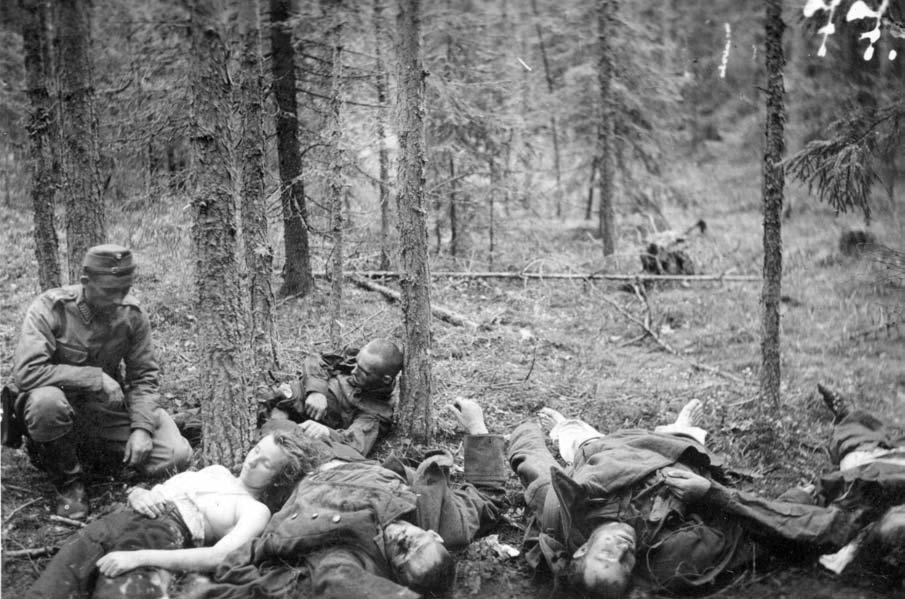 Suomalaisen sotilaan ottama kuva tuhotusta venäläispartiosta Maaselän kannaksella kevättalvella 1943. Puuta vasten nojaa kuollut venäläinen naissotilas, jolta on riisuttu pusero.