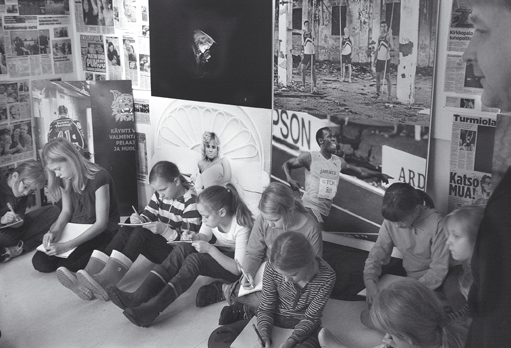 Pispan koulun reportterit lehtikuvanäyttelyssä Vierailulla Pispalan kirjastossa... Mika kertoo, että kuvaaminen on alkanut helpottua vuosien 1997 ja 1998 jälkeen digiajan myötä.