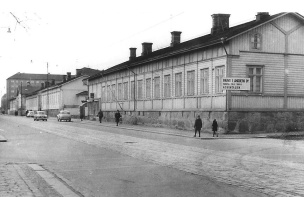 Puutalot poistuivat Itäisenkadun varsilta yksi toisensa jälkeen. Talon nurkalla näkyy rakennusliikkeen kyltti. Kuva vuodelta 1966, J. Salmi. kiekossa.