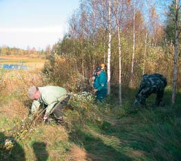 Pulkkilassa kuusitolpat kuorittiin ja maanalainen osa hiillettiin nuotiolla lahon kestäväksi. Samalla porisi punamultapata. Oppaana Ilpo Väisänen.