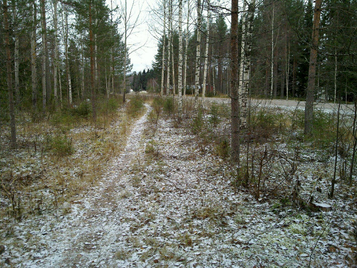 12 Vanhatie 6, taustalla, edessä olevan tien jatkeena, risteyksestä kt 66:n varteen. Etualalla vanhaa asfaltoitua kt:66:tta, jonka jatke hylätty nykyistä risteystä uusittaessa. Etelään.