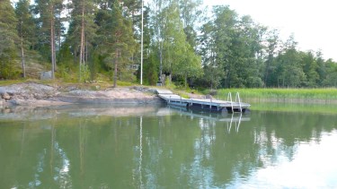 Vasemmalla varasto, kunto tyydyttävä. Sijainti talon itäpuolella. Polku vie alas laiturille. Eteläpihan reunassa kalustusta talon puolella näkymällä rantaan keinun takaa.