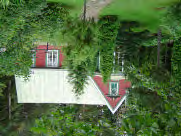 Ikkunapuitteet ovat valkoisia, punaisin ja sinisin tehostevärein listoituksissa. Hirsipinta on tummaksi tervattu(?)ulkoasussa saattaa havaita viitteitä Norrkullan turistihotelliin.