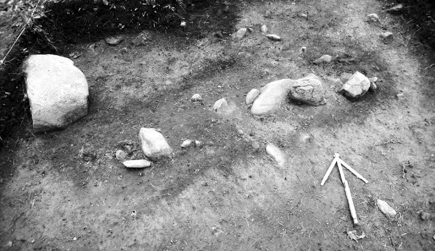 Ristimäen ruumishaudat erottuvat maassa tummempana läikkänä. Kuvassa vuonna 2010 tutkittu hauta. rään kivikaudelle ajoitettu asuinpaikka.