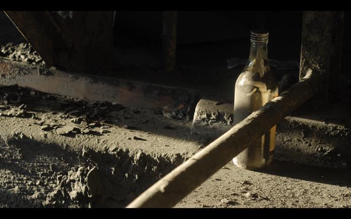 27 KUVA 2. Pölyinen pullo henkii mennyttä elämää. Kuvakaappaus elokuvasta Hanasaari A (2009).