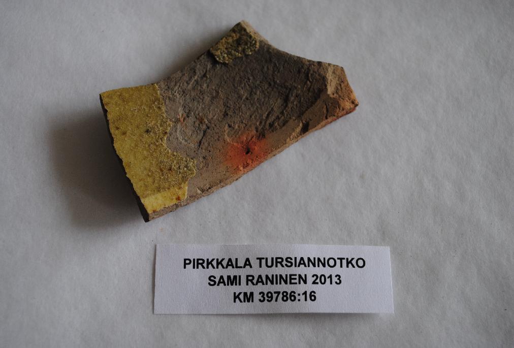 KM 39786 PIRKKALA PIRKKALANKYLÄ (BIRCALA) KM 39786 ja TURSIANNOTKO C-v-alue 28. Kivisavikeramiikka, 1 kpl Tieluiskan täyttömaan seasta.
