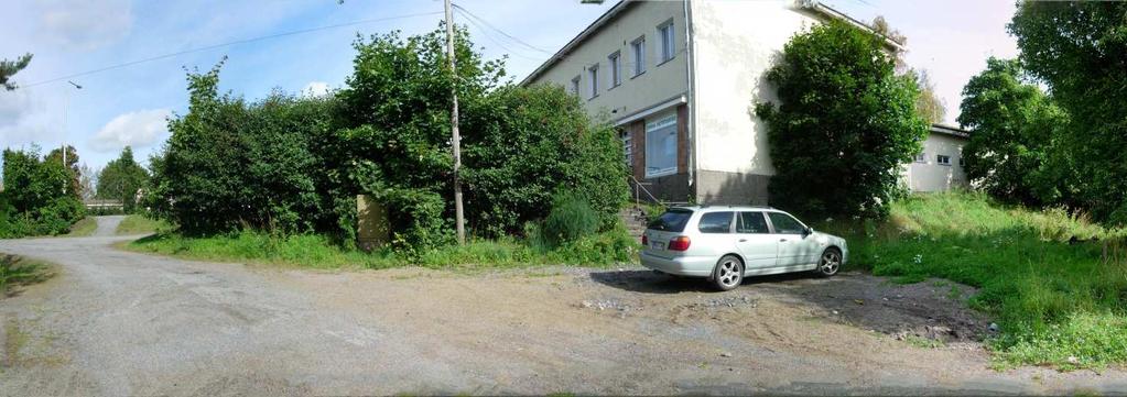 Rakennuksen länsi- ja luoteispuolella on tiloissa toimivan autotarvikeliikkeen asfaltoitu parkkipaikka ja muokattu, soralla päällystetty piha-alue, joka rajautuu tontin länsipuolitse kulkevaan