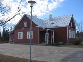 Koulurakennus; Ketolanperäntien varrella sijaitseva, vankan puuston ympäröimä koulualue.