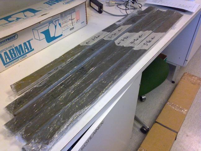 a) Magneettisen suskeptibiliteetin mittausta Bartingtonin MS2C -mittalaitteella ja b) avattuja sedimenttikooreja Bartingtonin MS2E laitteen suskeptibiliteettimittauksia ja stratigrafian määrittämistä