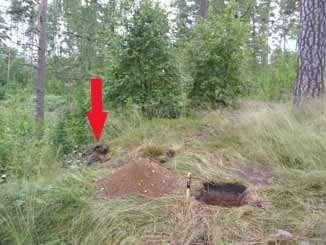 Kuva 10. Koekuoppa 2 ja löytökohta 1 hiekkakuopan reunassa nuolella merkittynä, kuvattu lounaasta. (DG2633:6/Ulla ) nähtävästi valunut hiekkakuoppaan.