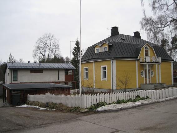 selkeän huvilan arkkitehtuuria hallitsee voimakas taitekatto ja pienellä parvekkeella katettu näyttävä