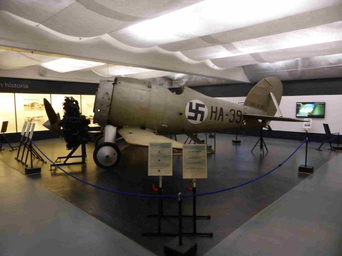 Näyttely ja Gloster Gamecock Asetettiin Haukka näyttelytilassa vaakalentoasentoon nostamalla koneen pyrstö metallituen varaan. Kiinnitettiin runkoon alasiivet.