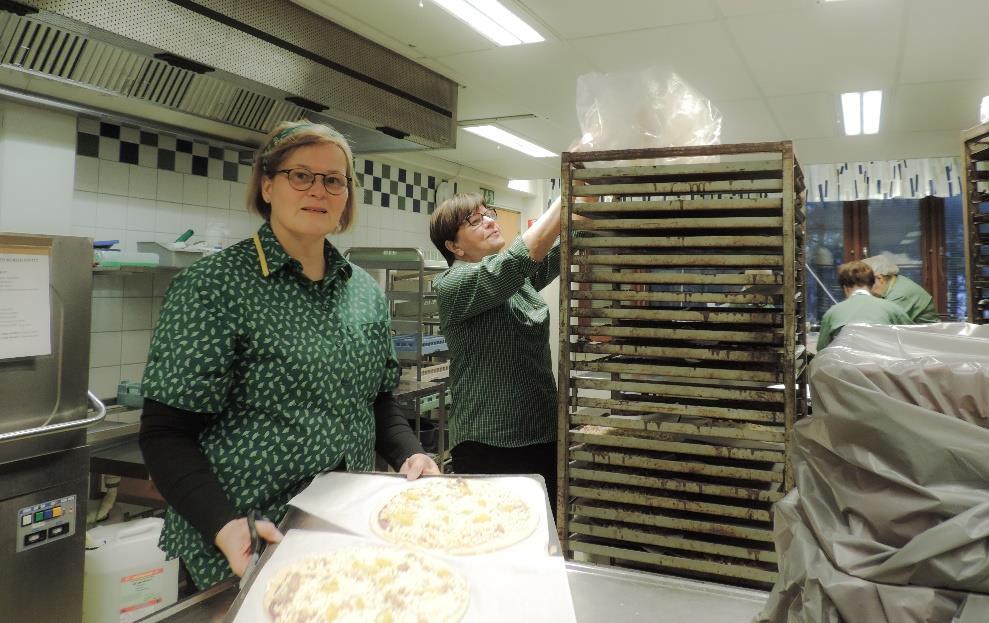 Sirkka Pouru (vas.) ja Marjut Virtanen auttoivat leipomossa tehtyjen pizzojen paistamisessa. Leipomon tekemät pizzat paistettiin keittiön uunissa. Salin puolella herkut maistuivat ja tuoksuivat.