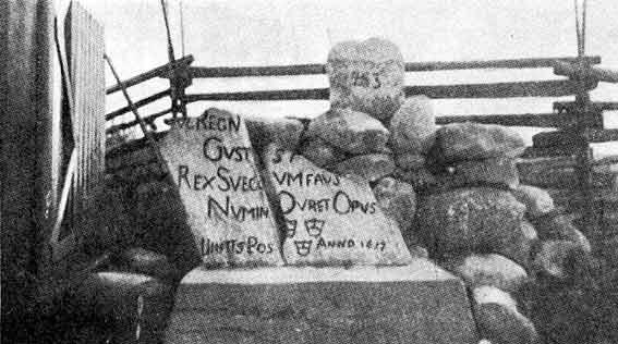 KUVA: STOLBOVAN RAUHAN RAJAN KIVI MANSSILASSA. KAHTIA HALJENNUT KIVI KIINNITETTIIN 1900-LUVULLA BETONIJALUSTAAN. KIVESSÄ NÄKYY KOLME KRUUNUA SEKÄ NIIDEN VIERESSÄ OIKEALLA ALHAALLA ANNO 1617.