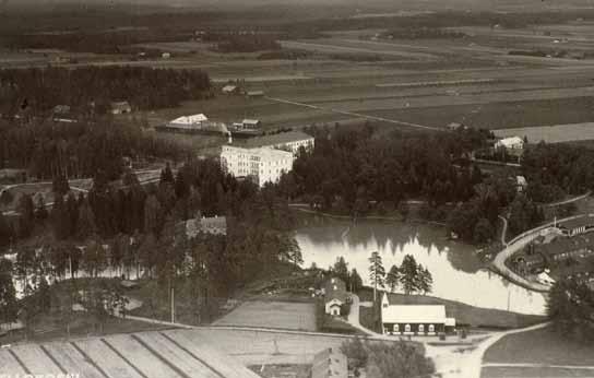 Ilmakuva 1930-luvun alkupuoliskolta. Keskitalon vasemmalla puolella näkyy pesularakennuksen kattoa ja taustalla, Vanhan viertotien toisella puolella Suomelan tilan uusi karjatalo ja asuinrakennus.