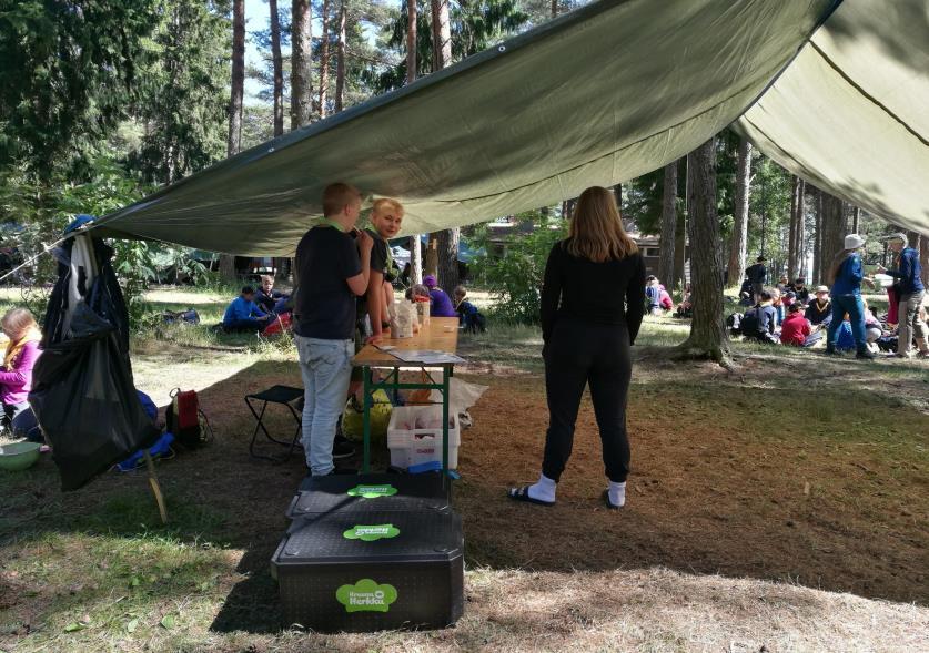 Kuvio 9. Reippaat partiolaiset The Mud Kitchenin työtehtävässä (Sonja Nieminen 2017). Raaka-aineita säilytettiin leirin keittiön lainaamissa styroksi-laatikoissa, jotta ne säilyivät paremmin.