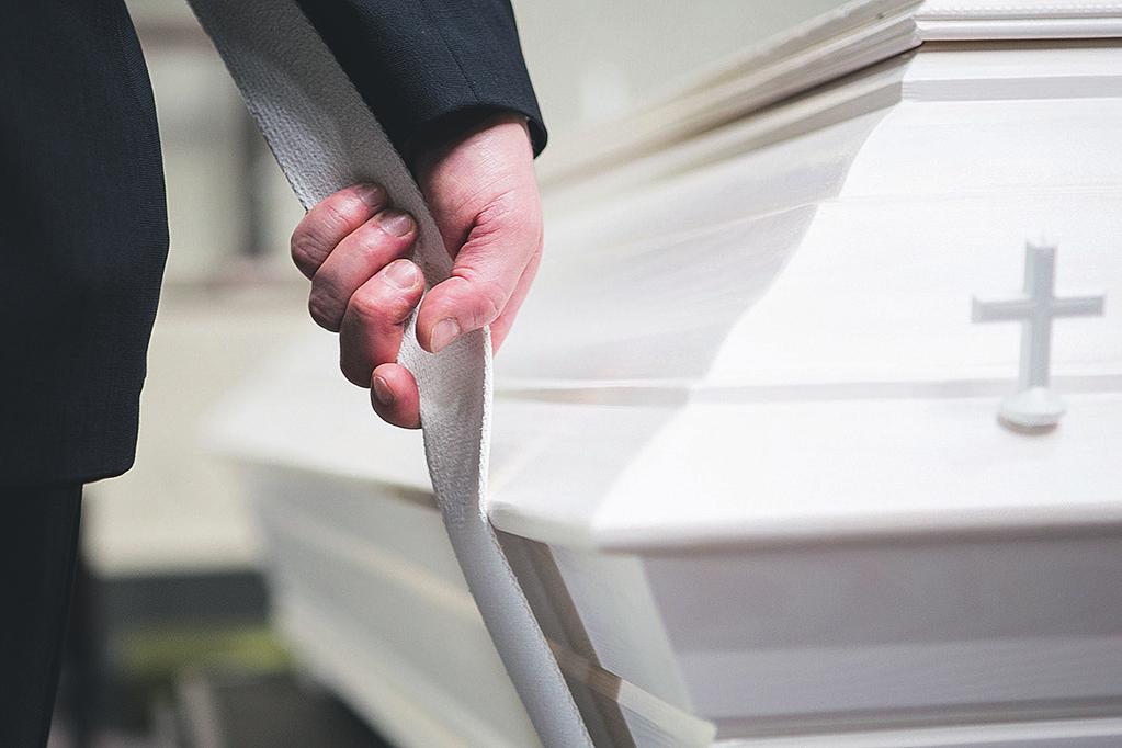 Haudalla seurakunnan työntekijä ohjaa arkun laskemista. Vanhan kristillisen tavan mukaan vainaja haudataan siten, että hänen kasvonsa ovat ylösnousemuksen suuntaan, itään päin.