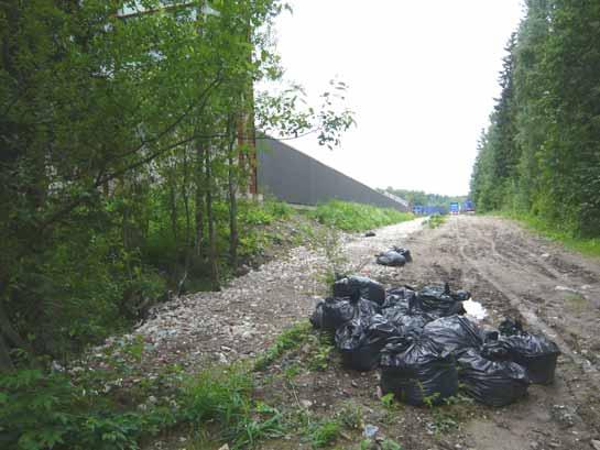 50 (116) Kuva 25. Viereiselle virkistysreitille näkyy laitosalueen pohjoisreunan aita ja Tauskontien jatke, joka on päällystämätöntä.