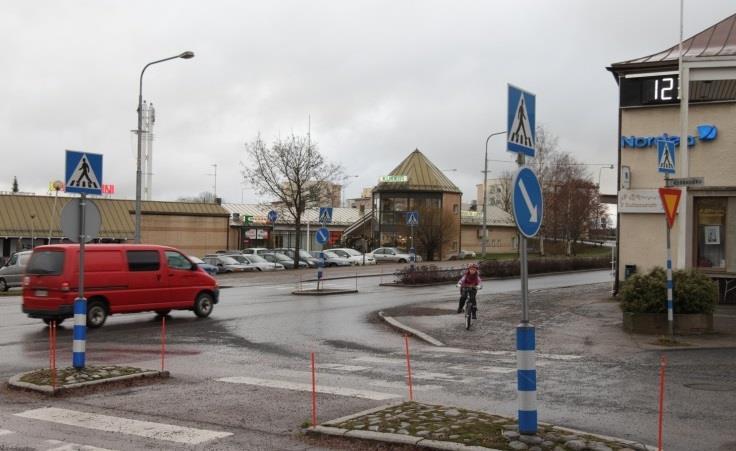 Lähempänä katulinjaa sijaitsee pienempi liikerakennus, joka tuo katukuvaan postmodernistisen vivahteen torneineen.
