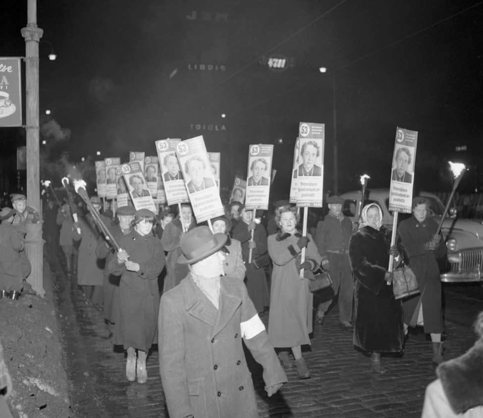 Yrjö Lintunen Naisten vaalikulkue Helsingissä 1954. Julisteissa erottuu numero 53, Kaisu-Mirjami Rydberg. Kansanedustajana 1945 1947 toiminutta Rydbergia ei enää valittu eduskuntaan. Kansan Arkisto.