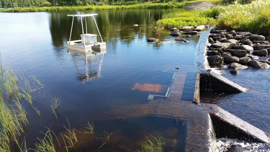 Kuva 7. Kalalaskuri Puodinkosken padon aukossa, lautalla sijaitseva aurinkokennosto sekä kalalaskurin ohjausyksikkö. Aukko oli suljettuna asennuksen aikana.