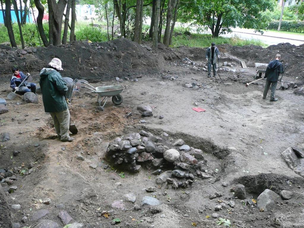 Etualalla on kaivausalueen länsiosan kaksi tulisijaa, jotka liittyvät 1800-luvun puistoon. Taustalla näkyy kaivausalueen eteläosan kivirakenne.