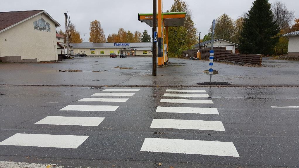 S-Marketin suojatie Suojatien sijaitsee keskellä jäsentelemätöntä tonttiliittymää, jossa on jalankulkijoiden lisäksi kaupalle ja kylmäasemalle suuntaavaa autoliikennettä.