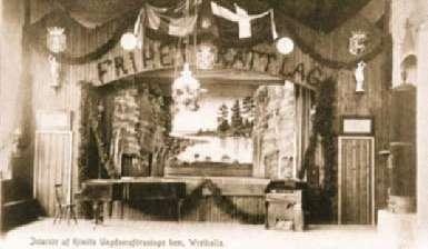 museovirasto Seurantalojen alkuaikojen tunnelmaa nuorisoseurantalo Wrethallalla Kemiössä. Kirkkokamina luo lämmön ja öljylamput tuovat valon. Postikortti on leimattu vuonna 1906.