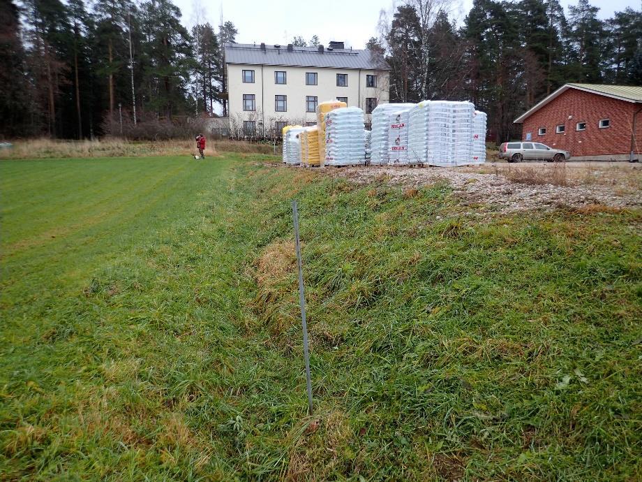 10 Hautaketo/Emäntäkoulun aluetta. Muinaisjäännösrekisterin pistetieto sijoittaa muinaisjäännöksen punatakkisen miehen (T. Sepänmaa) oikealla puolelle.