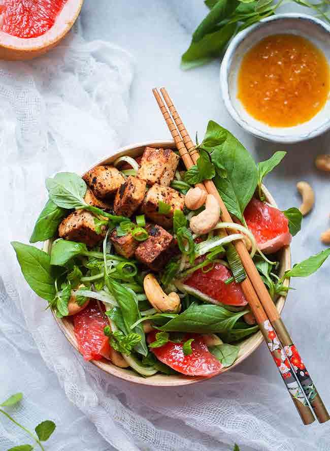 TOFU-KURKKUNUUDELISALAATTI (3 ANNOSTA) 1 paketti marinoitua Jalotofua 1 iso kurkku 1 nippu thai-basilikaa tuoretta minttua 2 dl silputtua kevätsipulia 1 iso verigreippi 100 g suolattuja