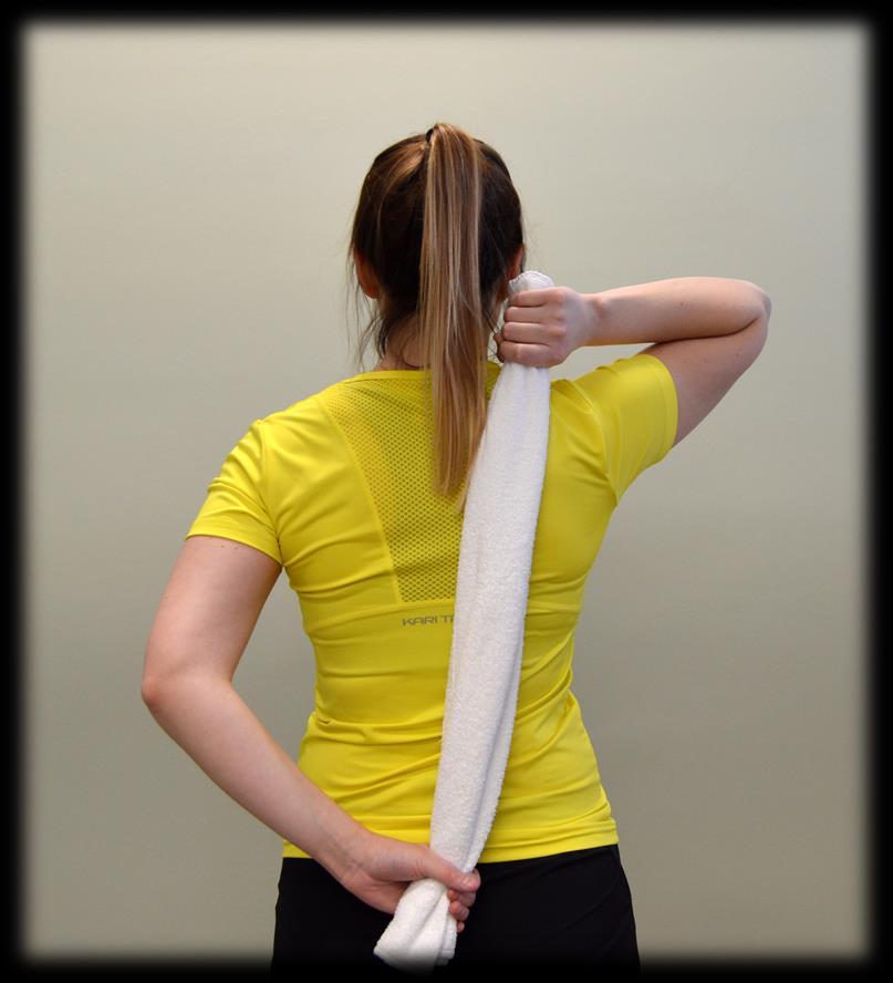 Vie kuntoutettava yläraajasi varovasti alaselällesi kämmenselkä selkään päin ja ota kiinni pyyhkeen toisesta päästä.