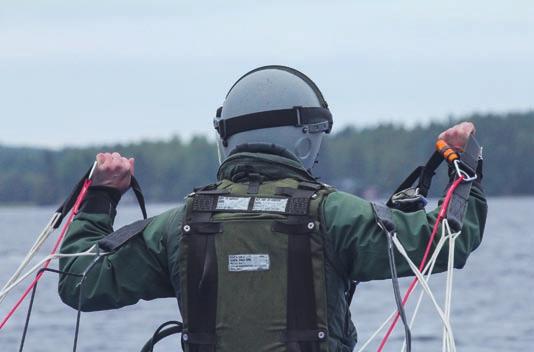 Hinauslaskuvarjoharjoitus nostaa korkeuksiin ja kastelee Seisot ponttonilautan reunalla tukevassa asennossa kädet ojennettuna kohti taivasta.