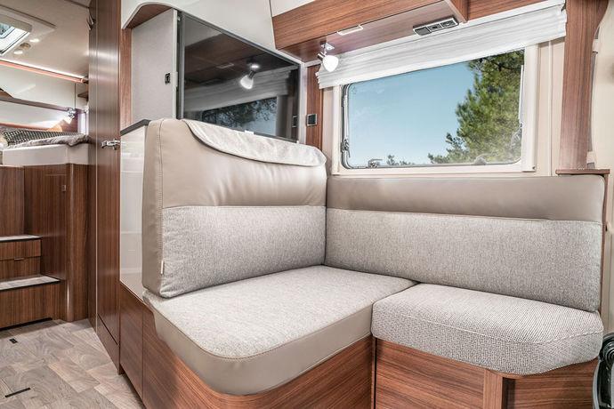 HYMER B-Klasse ModernComfort 580 -mallin istuinryhmä tässä tilauksesta (ilman lisähintaa) saatava Noce Cognac -kalustesävy yhdistettynä vakiona saatavaan Delfi-verhoilukankaaseen.