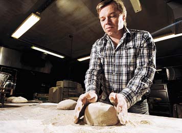 Luomuruista naapurista Junnilan leipomon yrittäjäomistaja Jari Junnila esittelee isännän ottein leipomonsa varastossa seisovia suuria jyväastioita.