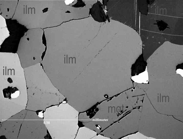 Oksidit harmaana silikaatit mustana. Mikroskooppikuva samasta näytteestä oikealla. Mittajana 0.5 mm.