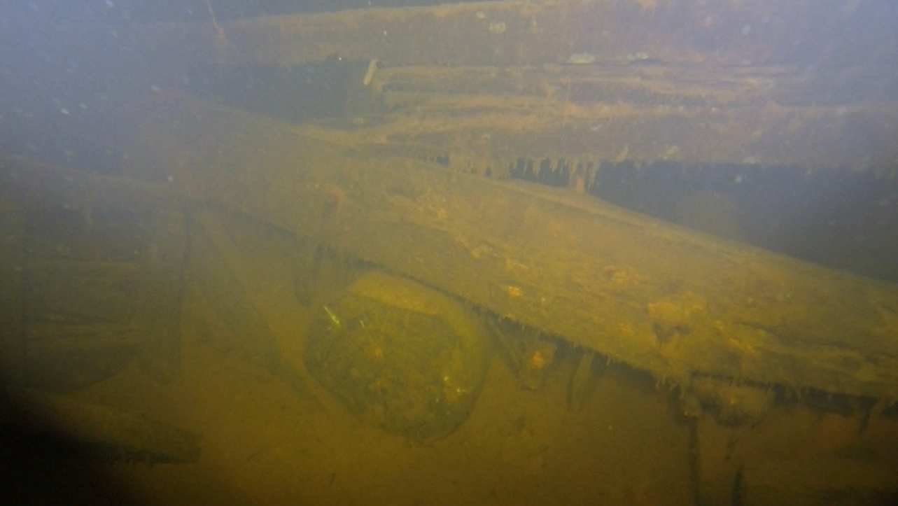 22 Kuva 10. Styyrpuurin kylkeä hylyn sisäpuolella. Pohjalla on runsaasti sedimenttiä. Parras on irronnut ja tippunut osittain sisään. Määrittelemätön puuosa makaa kuin aseteltuna veneen sisällä.