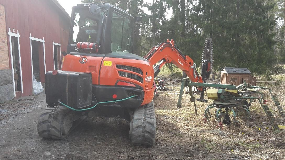 Kuva 14. Telakaivinkone Mensen raivauspäällä. Kuvassa näkyy tehoaineen säiliö ja letku, jota pitkin aine menee raivauspään terälle.