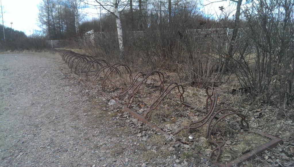 Kuva 30 Vääntyneitä rengastelineitä, pysäköiminen on käytännössä mahdotonta näille paikoille (Kuva Henri Luoto 2016). Paikoitellen kasvillisuus kasvaa telineiden lävitse.