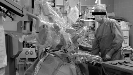 Kuva 5: Robotti leikkauksen aikana. Avustava kirurgi näkyy oikealla. 5.2 Haasteet: epävarmuustekijät, monimutkaisuus ja sisäiset ristiriidat Tutkimuksessamme analysoimme robottikirurgiaa toimintana perustehtäväanalyysin (Norros, 2004) kautta.