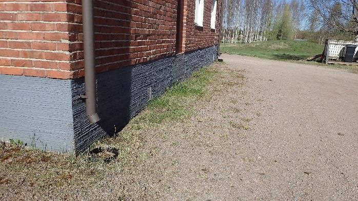 Kuva 5. Syöksyputken alla oleva rännikaivo on roskainen ja syöksyputkenpää on korkealla kaivoon nähden. Kuva 6. Sadevesikaivo rakennuksen päädyssä hätäpoistumistien edessä.