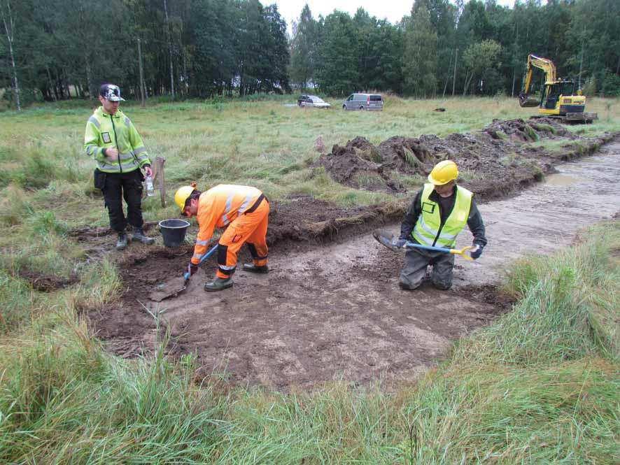 Kuva 4. Arkeologit Kalle Luoto ja Janne Rantanen puhdistamassa koeoja 7 mineraalimaan pintaa. Kuvassa myös kaivinkoneen kuljettaja Oskari Oja. Kuvattu luoteesta.