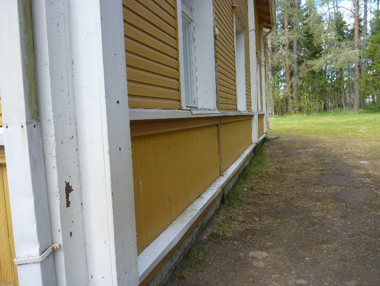 Maanpinta on tasainen rakennuksen kaikilla sivuilla.