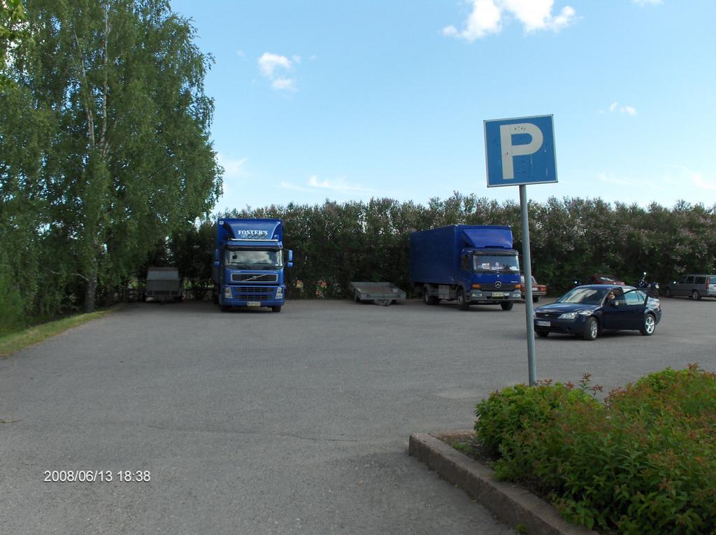 18 Keskusta Urheilukadulla sijaitsevalla yleisellä parkkipaikalla oli pysäköitynä yksi rekka ja yksi kuorma-auto. Tien toisella puolella on kerrostaloja.