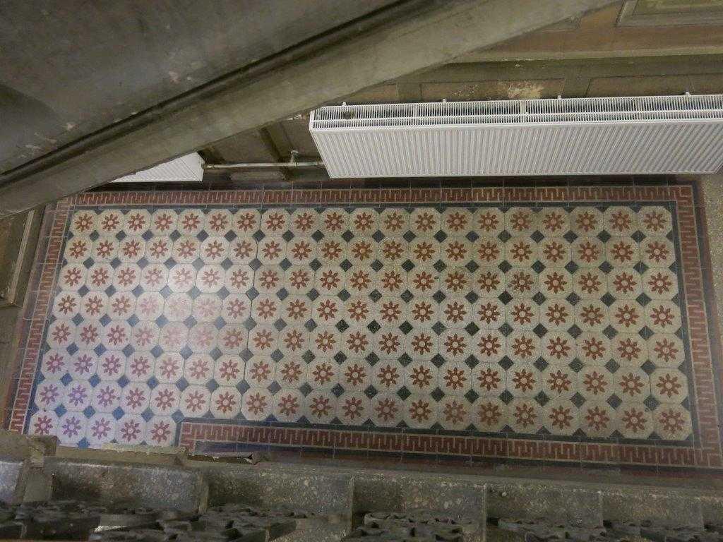 muotoiseen eteistilaan, jonka lattia on tehty geometrisesti kuvioiduista mosaiikkibetonilaatoista. Lattialaatoitus kehyslaattoineen jäljittelee mattoa.