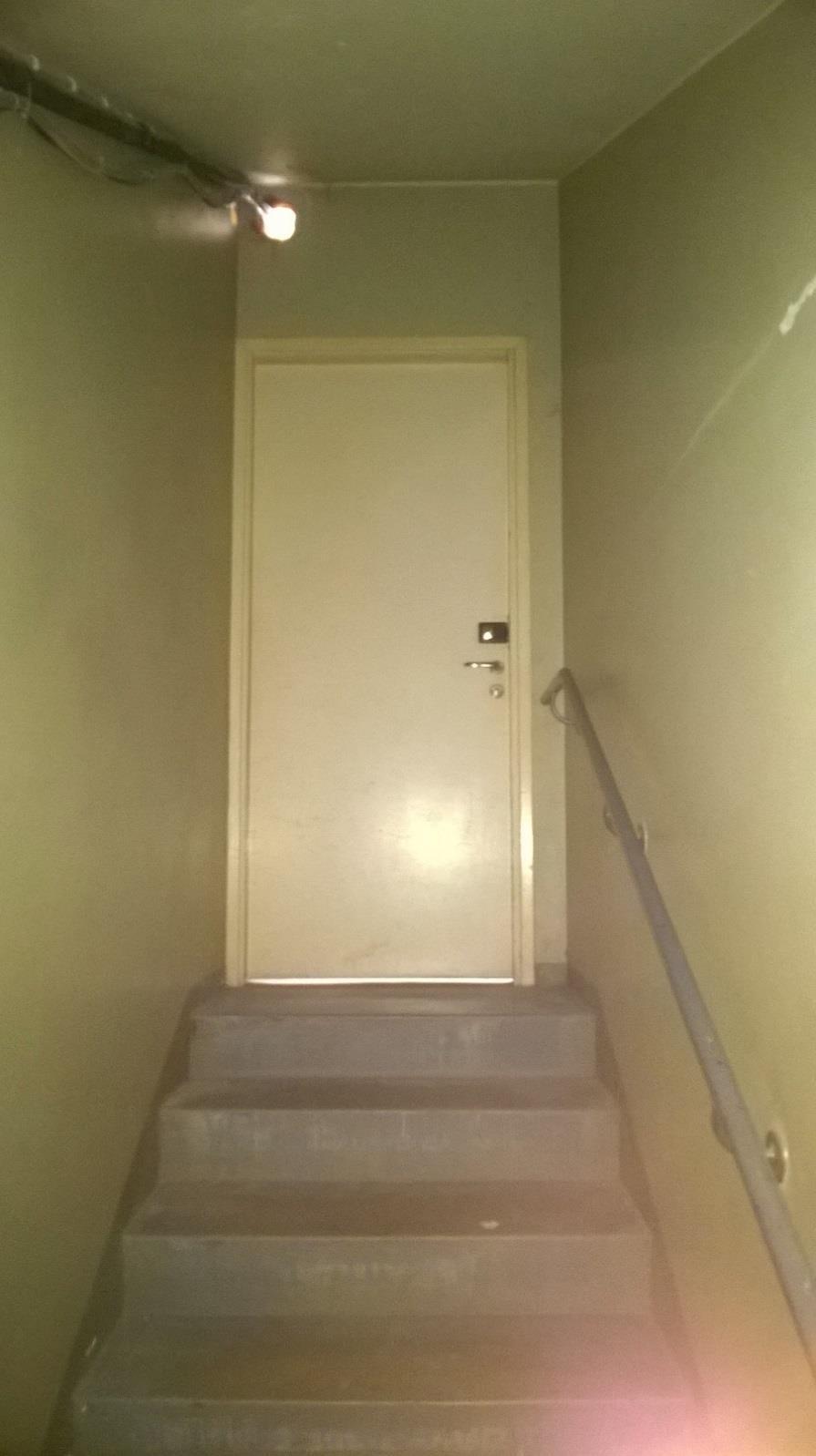 91 Yllä oleva kuva on otettu asuinkerrostalon maanalaisesta kerroksesta. Kuvassa näkyvä ovi johtaa porraskäytävään.
