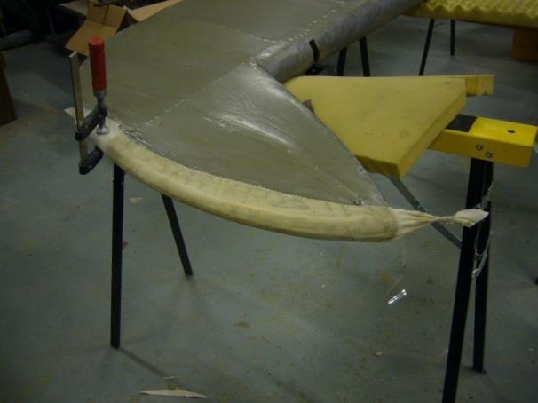Tukivanerin läpi kiinnitettiin ohuesta metallilangasta lenkki, jonka avulla liimapintainen viilulappu saatiin pujotettua kankaassa oleva reiän lävitse kankaan alapinnalle.