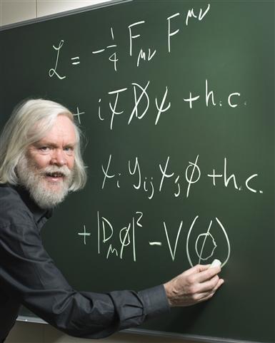 CERNin teoreetikko John Ellis kirjoittaa taululleen standardimallin matemaattisen kaavan.