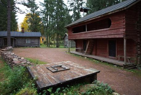 Kuusien varjostamalla tontilla sijaitsevat piharivi, luhtirakennu, paja, lato sekä punaiseksi maalattu Martan mökki. Kuvat: Jaakko Ojala.